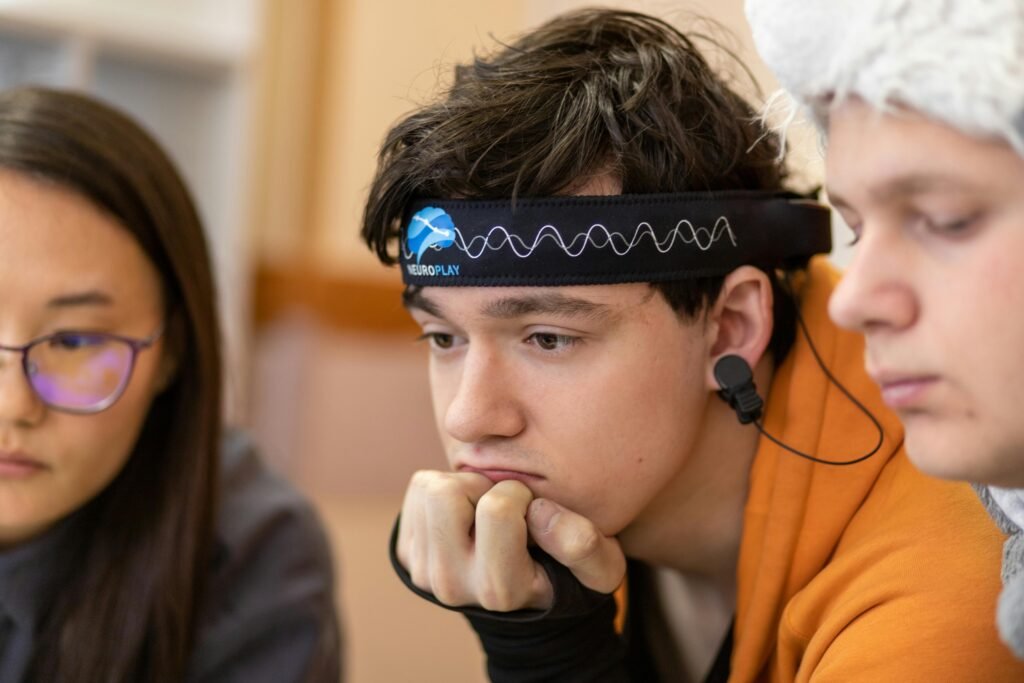 Teenagers engaged in a study session using a neurotech headband for focus and concentration.